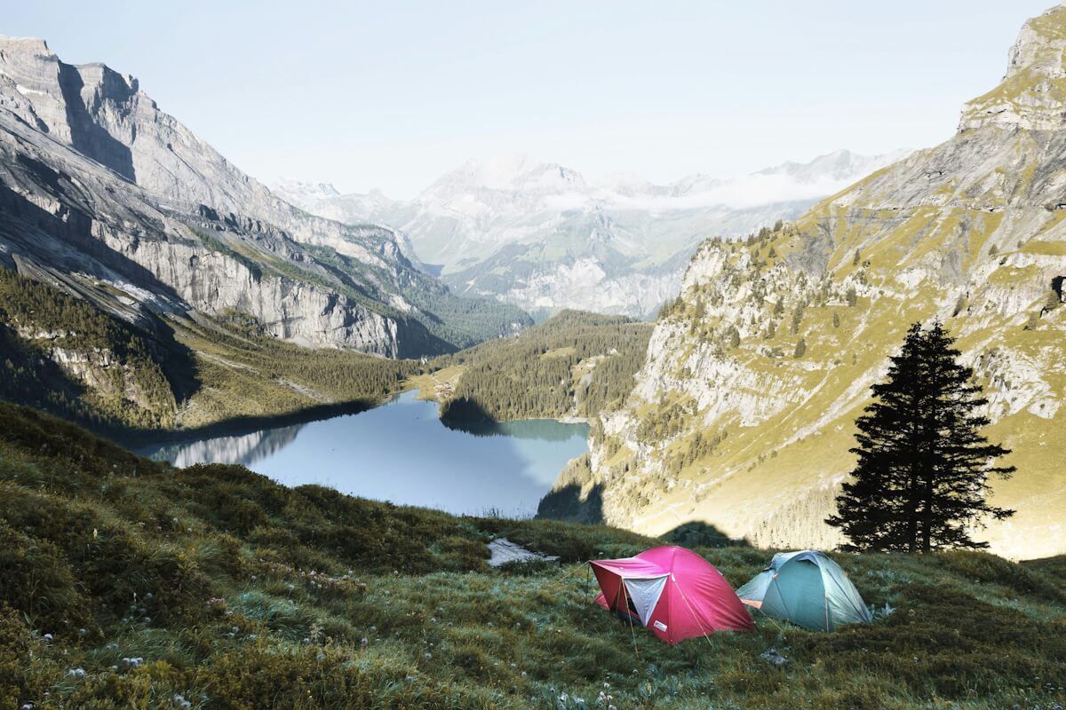 Zwei Zelte auf Alpenwiese in der Schweiz mit See im Hintergrund